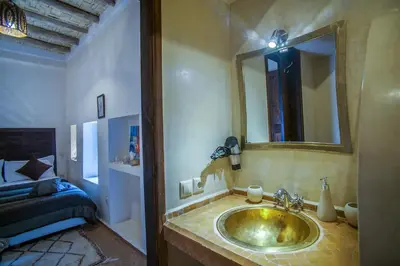 a bathroom with a sink with a mirror and a bed at Riad Haraka in Marrakech