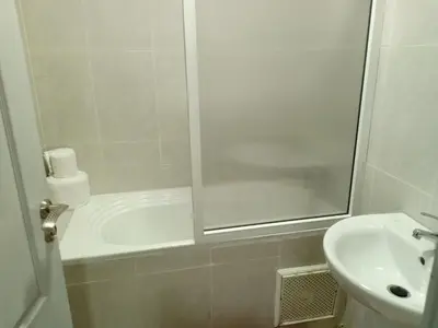 a white bathroom with a shower and a sink at Appartement rouge 6 perso in Marrakech
