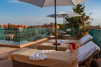 two beds on a balcony with an umbrella at Villa Soraya Hammam & Jacuzzi in Marrakech