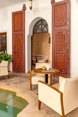 a living room with a table and chairs and a pool at Riad Luciano Hotel and Spa in Marrakech