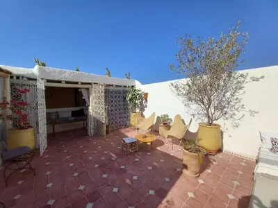 a patio with chairs and a table and a tree at Riad Alqimam in Marrakech