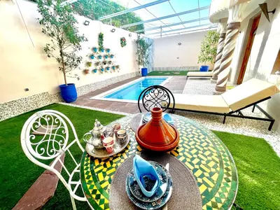 a patio with a table and a swimming pool at Villa Paradis in Marrakech