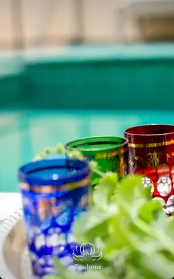 three colorful cups sitting on a plate next to a plant at Riad Zouhour in Marrakech