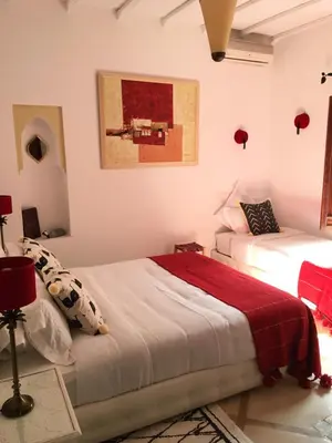 a bedroom with two beds and a painting on the wall at Riad Dar Kasal in Marrakech