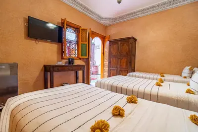 a bedroom with two beds and a tv on the wall at RIAD VILLA SIDI BABA in Marrakech