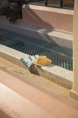 a hat sitting on the edge of a swimming pool at Riad Les Hirondelles Boutique Hotel and Spa in Marrakech