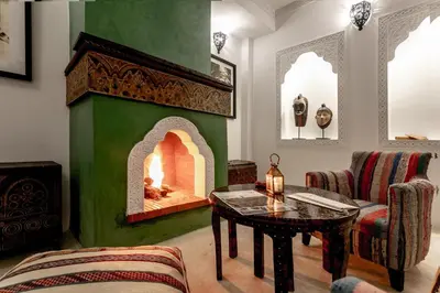 a living room with a green wall with a fireplace at Riad Hart Essoura in Marrakech