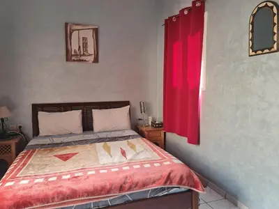 a bedroom with a bed with a red curtain at Riad BAB ALMADINA in Marrakech
