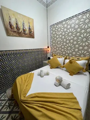 a bedroom with a large white bed with yellow pillows at Dar KHALID in Marrakech