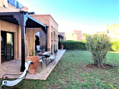 a garden with a bench and a table and chairs at Villa Mayrit, Villa estilo Riad en un entorno único in Marrakech