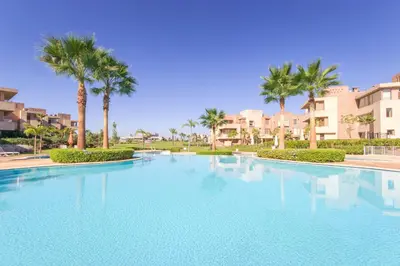 a large swimming pool with palm trees and buildings at Pool View With Garden in Prestigia - WIFI & Pool in Marrakech