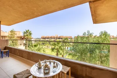 a balcony with a table and chairs and a large window at Escale de Charme - Prestigia Golf - Vue piscine in Marrakech