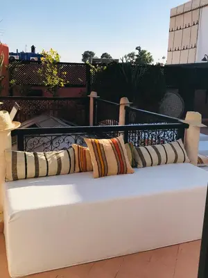 a white bench with pillows on a balcony at riad anrich in Marrakech