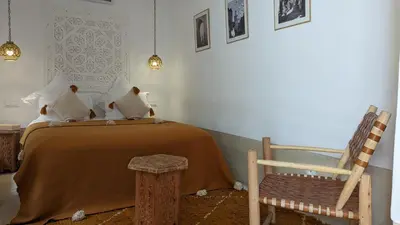 a bedroom with a bed and a wooden chair at Riad Dar Eternity in Marrakech