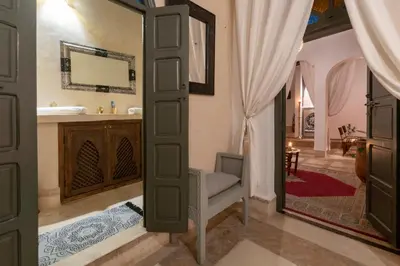 a bathroom with a mirror and a chair and a sink at Riad dar El Arsa Rooftop & jacuzzi in Marrakech