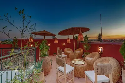 a patio with chairs and tables and umbrellas at Riad dar El Arsa Rooftop & jacuzzi in Marrakech