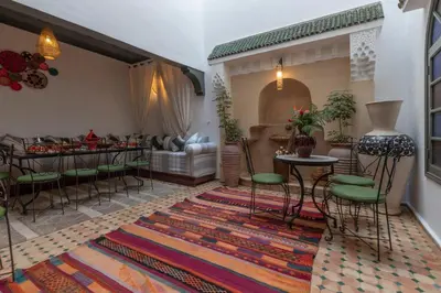 a living room with a table and chairs on a rug at Riad dar El Arsa Rooftop & jacuzzi in Marrakech