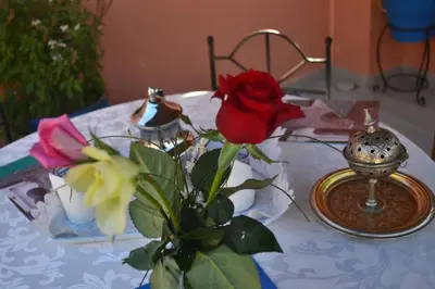 a table with a vase with a rose on it at Riad Hôtel Belleville Marrakech in Marrakech
