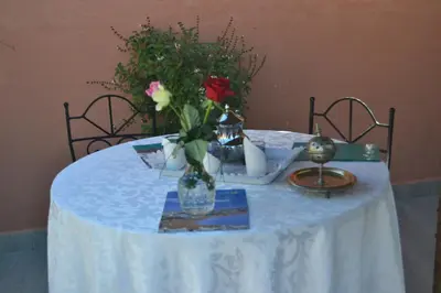 a white table with a vase with a rose in it at Riad Hôtel Belleville Marrakech in Marrakech