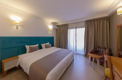 a bedroom with a large bed with a blue headboard at Hôtel Ibn Batouta in Marrakech