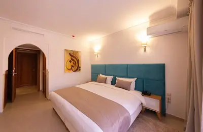 a bedroom with a large bed with a green headboard at Hôtel Ibn Batouta in Marrakech