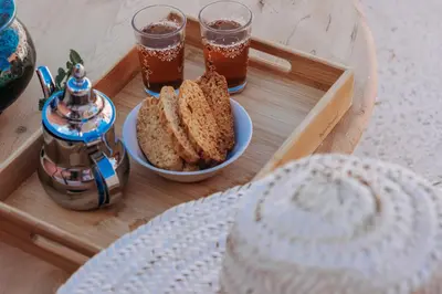 a tray with two slices of bread and two glasses of tea at Riad ANYSSA in Marrakech
