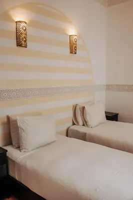 two beds sitting next to each other in a room at Riad ANYSSA in Marrakech
