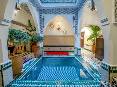 a swimming pool in a building with blue tiles at Riad Art & Emotions in Marrakech