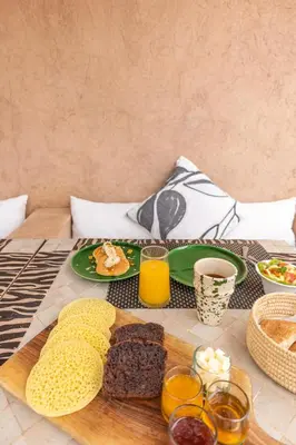 a table with two plates of food and two glasses of orange juice at Riad Baba Ali & Spa in Marrakech