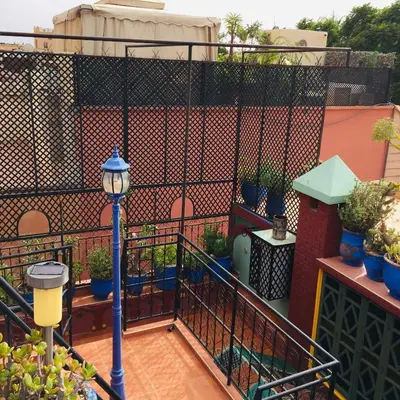 a balcony with a fence with potted plants and a street light at ALMARKAB Riad in Marrakech