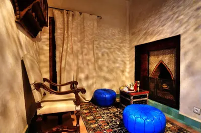 a living room with blue stools and a fireplace at Riad Aventurine in Marrakech