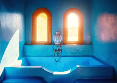 a blue bathroom with a tub with two windows at Riad Roxanne in Marrakech