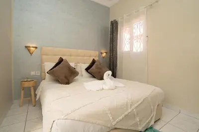 a bedroom with a white bed with a white swan on it at Résidence alqaria assiyahiya full private riad in Marrakech