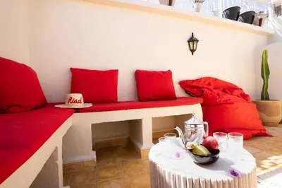 a living room with red pillows and a red bench at Résidence alqaria assiyahiya full private riad in Marrakech