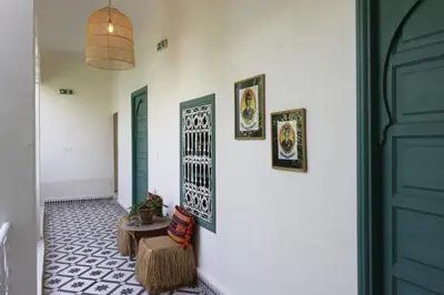 a hallway with green doors and a table and chairs at Riad NaaNaa Bed & Breakfast in Marrakech