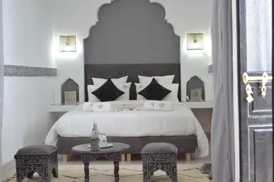 a bedroom with a large bed and a table at Riad le Voile d'Orient in Marrakech