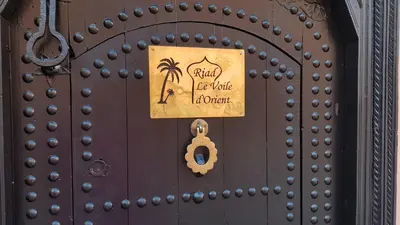 a door with a sign on it with a palm tree and a key at Riad le Voile d'Orient in Marrakech