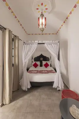 a bedroom with a bed with curtains and a chandelier at Riad le Voile d'Orient in Marrakech