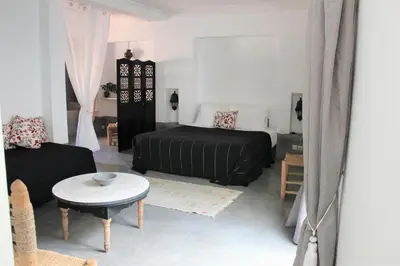 a bedroom with a bed and a table and a couch at Riad El Ouarda in Marrakech