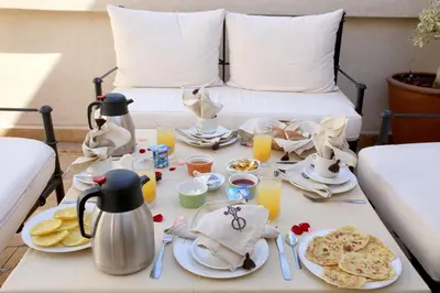 a breakfast table with food and drinks on a bed at Riad La Croix Berbere Deluxe in Marrakech