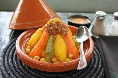 a bowl of food with carrots and beans and a spoon at Casa De Marrakech Riad Guest House in Marrakech