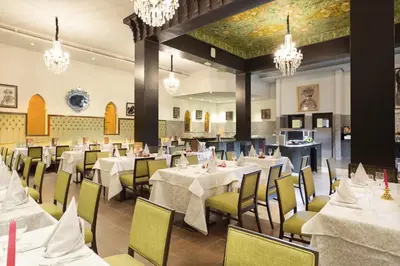 a dining room with tables and chairs and chandeliers at Hotel Riu Tikida Palmeraie - All Inclusive in Marrakech