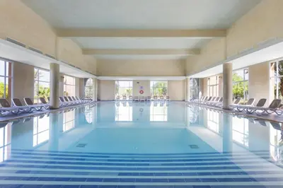 a large swimming pool with chairs in a building at Hotel Riu Tikida Palmeraie - All Inclusive in Marrakech