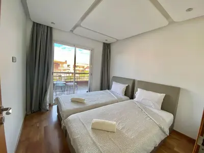 a hotel room with two beds and a balcony at RIAD GARDEN LUXURY AGDAL in Marrakech