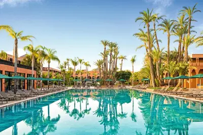 a swimming pool at a resort with chairs and palm trees at Hotel Riu Tikida Garden - Adults Only - All Inclusive in Marrakech