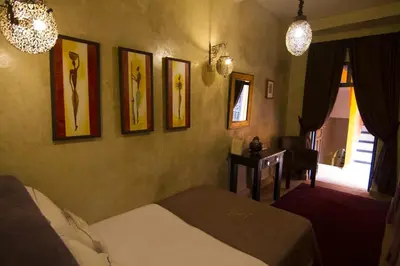 a bedroom with a bed and pictures on the wall at Riad Hermès in Marrakech