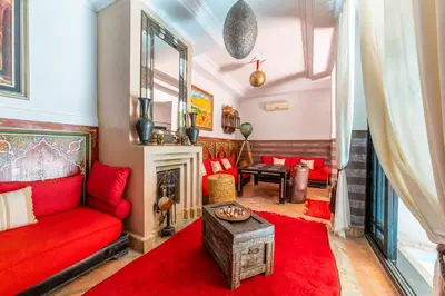 a living room with a red couch and a fireplace at Riad Espoir, Riad de charme en exclusivité dans la médina de Marrakech in Marrakech