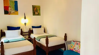a room with two twin beds and a chair at Riad Zarka By La Siredrah in Marrakech