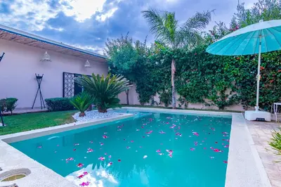 a swimming pool with an umbrella in a yard at VILLA MARIA - Famille uniquement in Marrakech