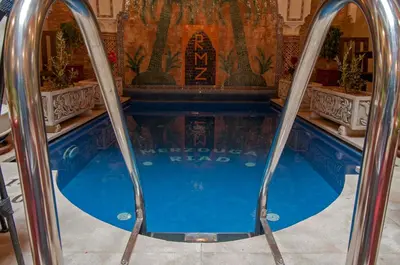 a swimming pool in a building with twoadders in it at Riad Merzouga in Marrakech